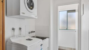 Una lavandería con lavadora, secadora y lavabo.