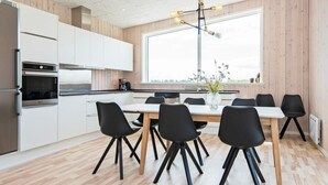 A modern kitchen with white cabinets, a dining table with black chairs, and a large window.