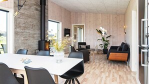A modern living room with a fireplace, a dining area with a white table, and a seating area with a sofa and chairs.