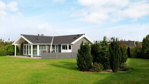 Een modern herenhuis met twee verdiepingen, een schuin dak, grote ramen en een omheinde tuin.