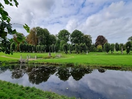 Un parque con un estanque, senderos y árboles.
