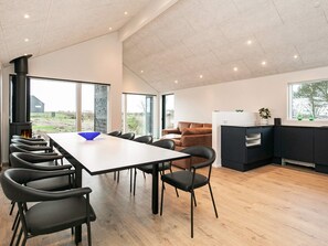 A modern kitchen with a dining area, a fireplace, and large windows.