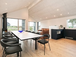 A modern kitchen with a dining area, a fireplace, and large windows.