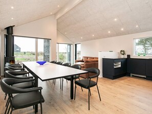 A modern interior with a dining area, a sofa, a kitchen, and a large window.