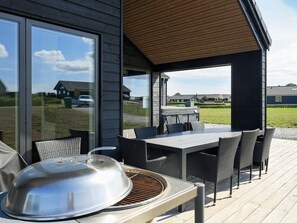 An outdoor patio with a grill, dining table, and chairs.