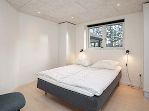 A modern bedroom with a bed, bedside lamps, a window, and a view of the outside. - 4 Star Holiday Home in Lokken (Lokken)