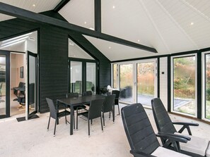 A modern interior with a dining area, black chairs, a table, and large glass doors leading to an outdoor space.