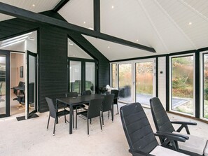 A modern interior with a dining area, black chairs, a table, and large sliding glass doors leading to an outdoor space. - 4 Star Holiday Home in Lokken (Lokken)