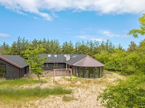 A modern house with a large deck, surrounded by dense forest. - 4 Star Holiday Home in Lokken (Lokken)