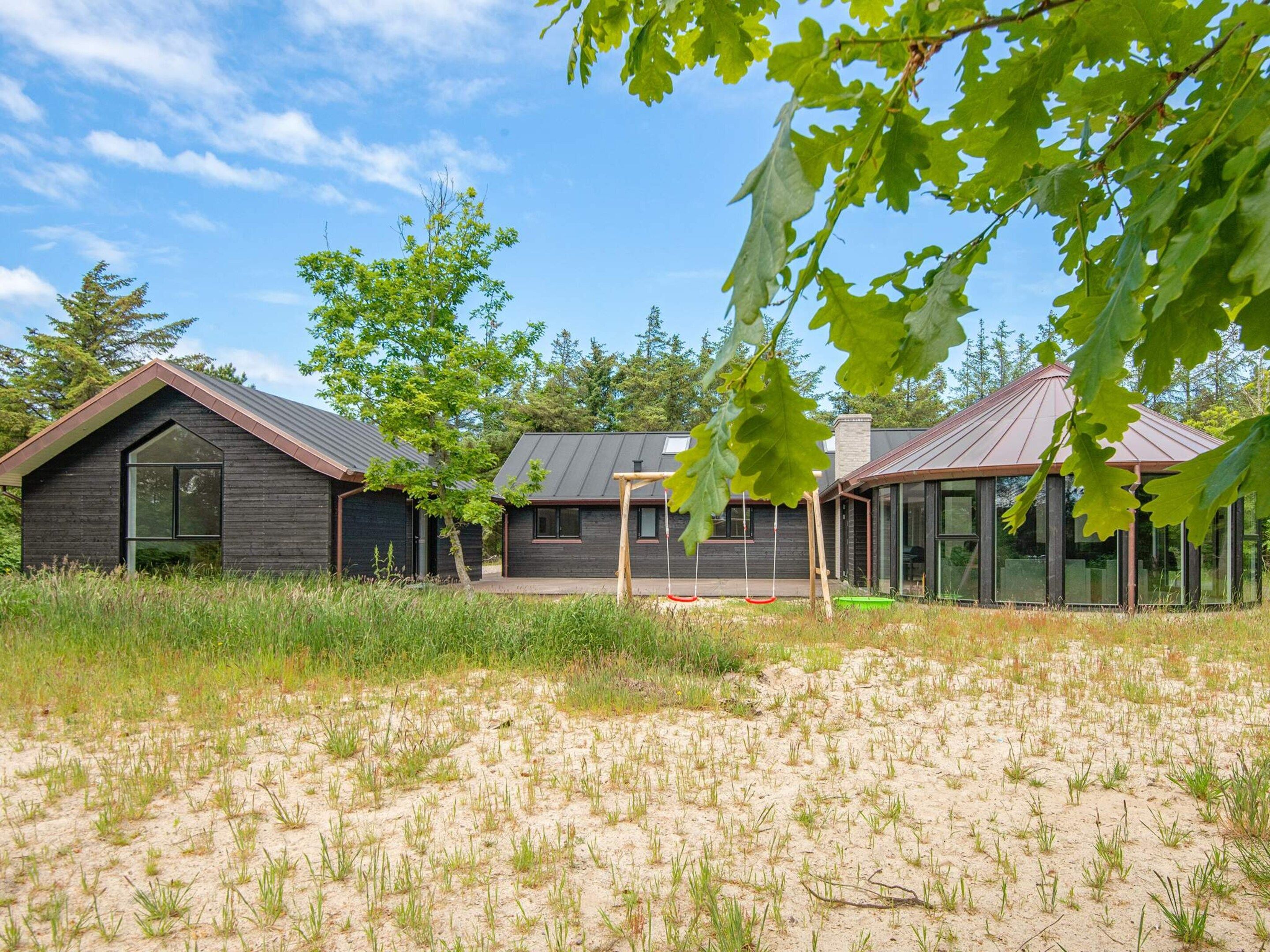 A modern house with a large window and a swing set in the yard.