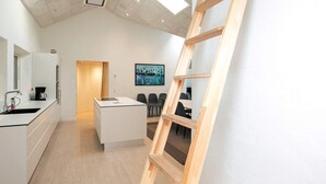 A modern kitchen with a central island, a coffee machine, and a painting on the wall. - 4 Star Holiday Home in Lokken (Lokken)