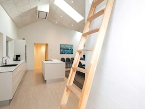 A modern kitchen with a central island, a coffee machine, and a painting on the wall. - 4 Star Holiday Home in Lokken (Lokken)