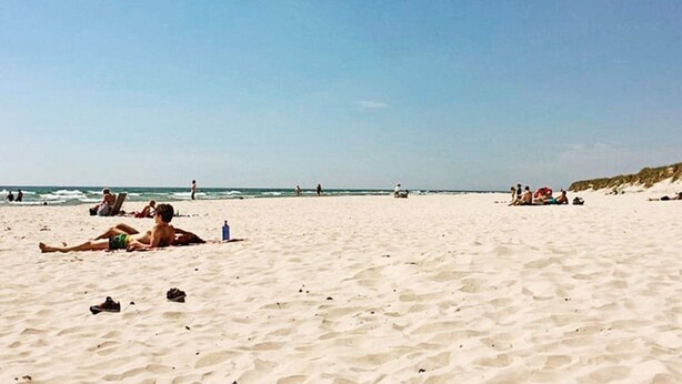 Een strand met mensen die zonnen en zwemmen.