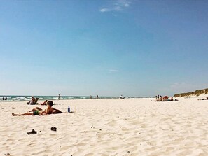 Una spiaggia con persone che prendono il sole e nuotano.