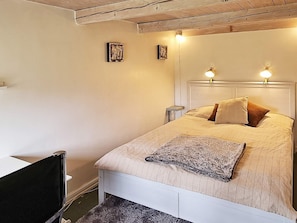 A bedroom with a bed, two bedside lamps, a nightstand, and a small table.