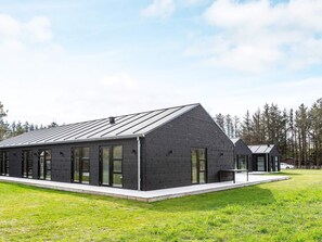 A modern building with a sloped roof, large windows, and a flat entrance area. - 5 Star Holiday Home in Lokken (Lokken)