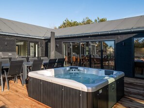 Un área moderna de hidromasaje al aire libre con terraza, asientos y un patio cubierto.