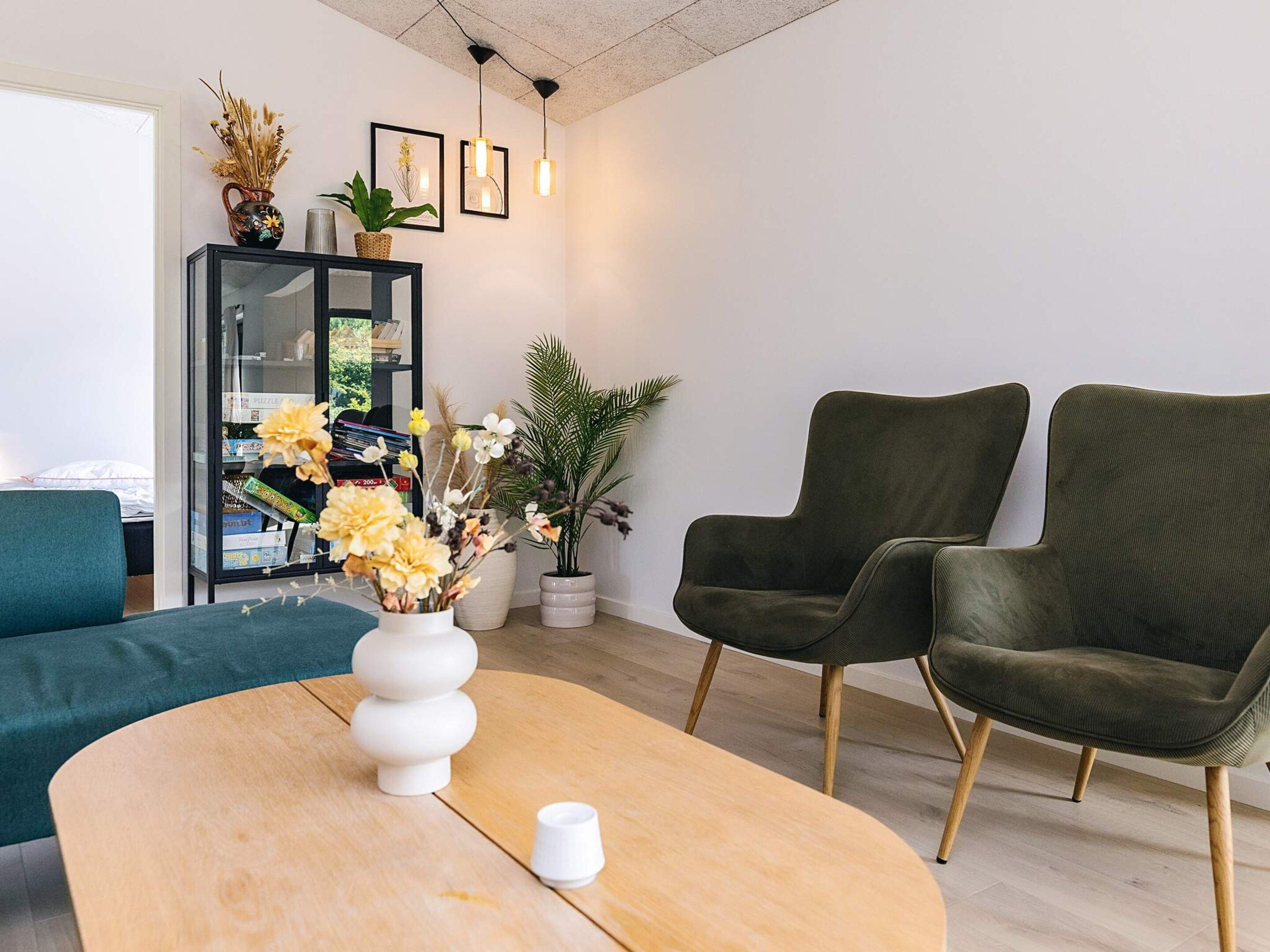 A modern living room with a sofa, two armchairs, a coffee table, and a bookshelf with decorative items.