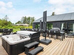 A deck with a hot tub, outdoor seating, and a covered grill area. - 5 Star Holiday Home in Lokken (Lokken)