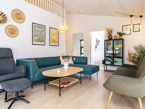 Un salon moderne comprenant un canapé, un fauteuil et une table basse, ainsi qu’une bibliothèque et des œuvres d’art décoratives accrochées au mur.