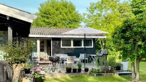 A small house with a covered porch, outdoor seating, and potted plants. - 6 Person Holiday Home in Tisvildeleje (Tisvildeleje)