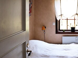 A room with a bed, a window with curtains, a wall-mounted lamp, and a radiator. - 3 Person Holiday Home in Mellerud-by Traum (Mellerud)
