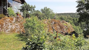 A modern house with a large glass window, surrounded by lush greenery and a rocky hillside. - 3 Person Holiday Home in Mellerud-by Traum (Mellerud)