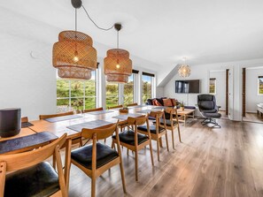 A modern dining area with a long table, multiple chairs, and two large wicker pendant lights. - 5 Star Holiday Home in Ringkobing (Ringkobing)