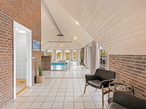 A covered outdoor area with a pool, brick walls, and a ceiling with wooden beams. - 5 Star Holiday Home in Ringkobing (Ringkobing)