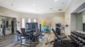 Et rummeligt fitnesscenter med varieret træningsudstyr, herunder styrkemaskiner og håndvægte.