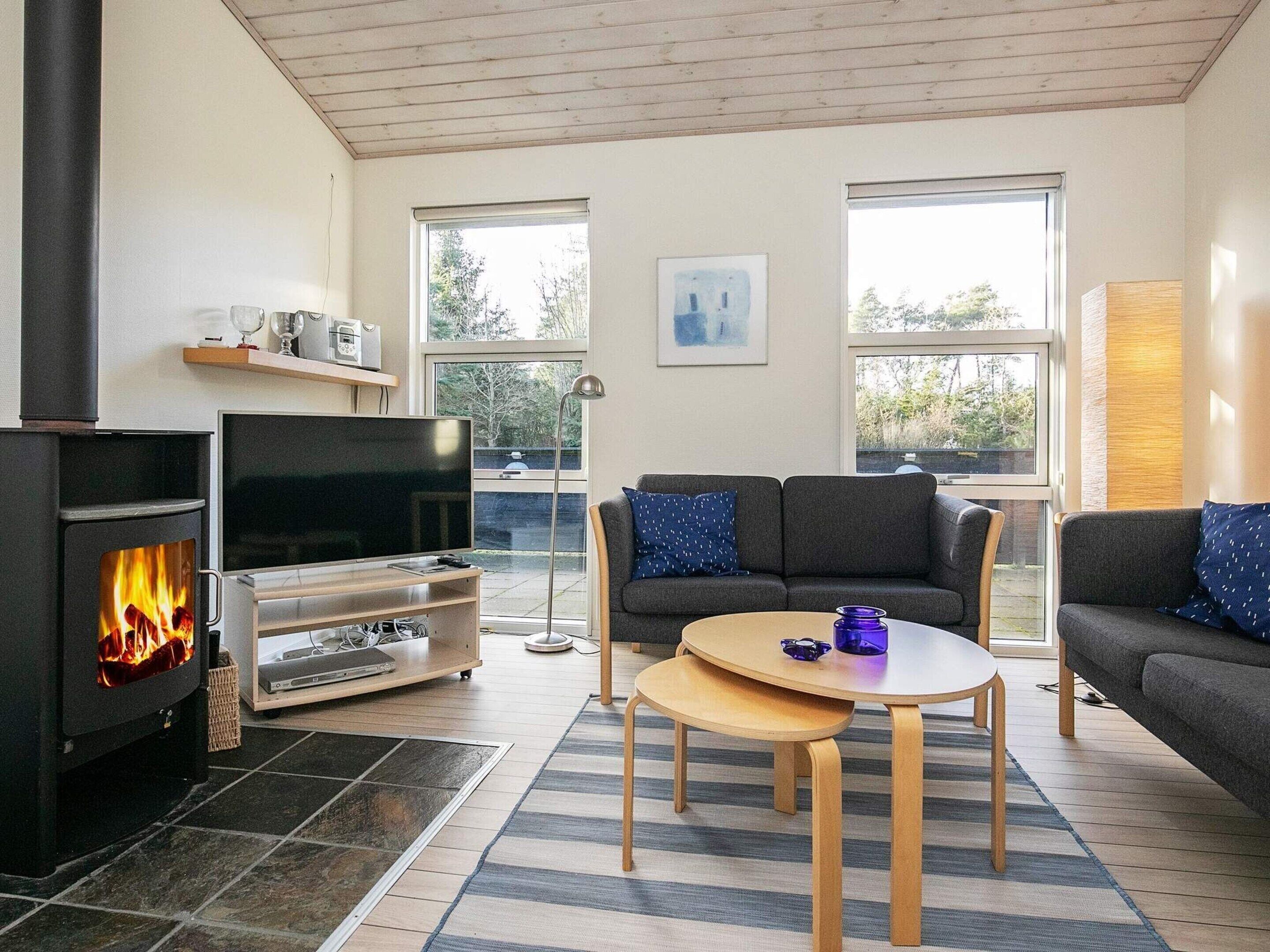 Una sala de estar con chimenea, televisor, sofá y mesa de centro.