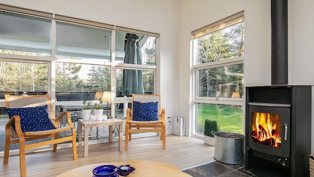 A cozy room with a fireplace, large windows, and wooden furniture. - 8 Person Holiday Home in Hals-by Traum (Hals)