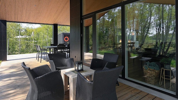 A modern outdoor dining area with wicker furniture and a glass enclosure.