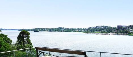 A wooden bench on a pier overlooking a calm body of water with a distant shoreline.