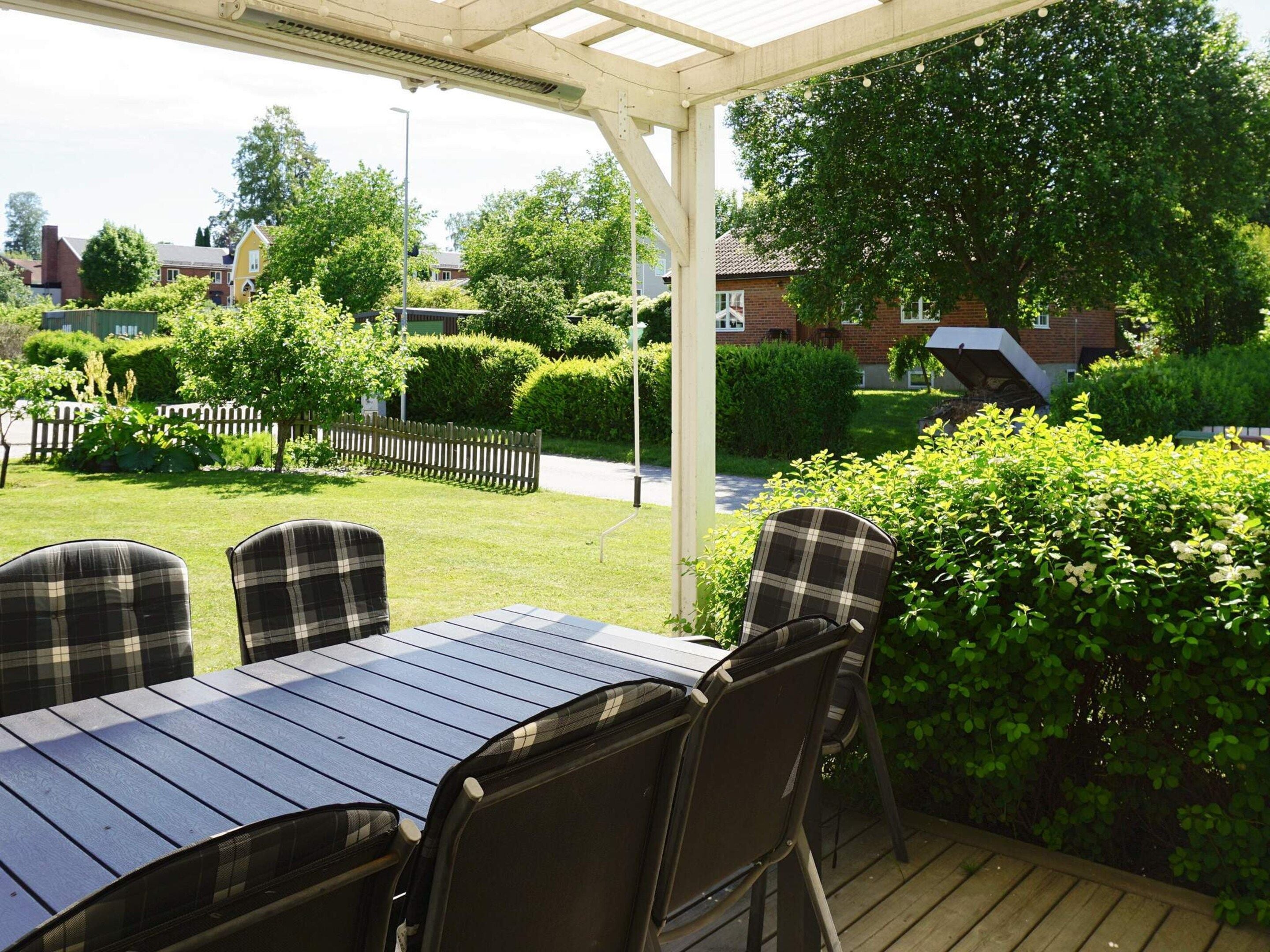 Une terrasse extérieure avec une table et des chaises, entourée de verdure et dotée d’une plateforme en bois.