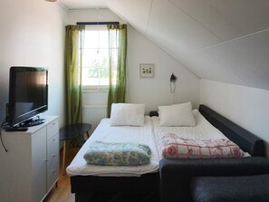A bedroom with a bed, a television, a desk, and a window with curtains. - 4 Star Holiday Home in Sollentuna (Sollentuna)