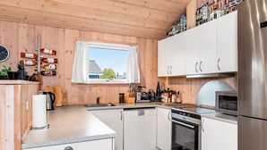 Una cocina moderna con paneles de madera, electrodomésticos de acero inoxidable y un ventanal con vistas a edificios.