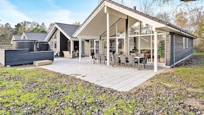 A modern house with a covered patio, large windows, and a well-maintained lawn. - 5 Star Holiday Home in Vaeggerlose (Vaeggerlose)