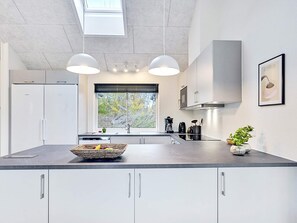 Eine moderne Küche mit einer großen Kochinsel, integrierten Geräten und einem Fenster mit Blick.
