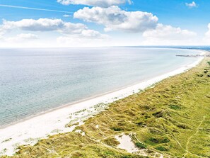 A coastal landscape with a sandy beach and grassy dunes.