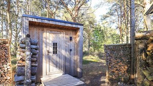 A wooden cabin with a door, a small window, and a wooden deck leading to it. - 5 Star Holiday Home in Albaek (Aalbaek)