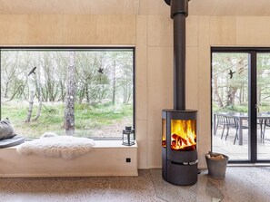 A room with a large window, a fireplace, and a seating area with a fur throw.