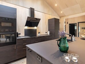 Une cuisine moderne dotée d’appareils électroménagers intégrés, d’un grand îlot central et d’un vase décoratif.