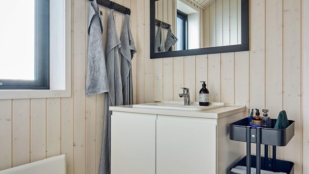 A bathroom with a white sink, a mirror, and a towel rack. - 8 Person Holiday Home in Aakirkeby (Akirkeby)