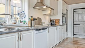 Une cuisine moderne avec des armoires blanches, une hotte de cuisinière en acier inoxydable et un lave-vaisselle.