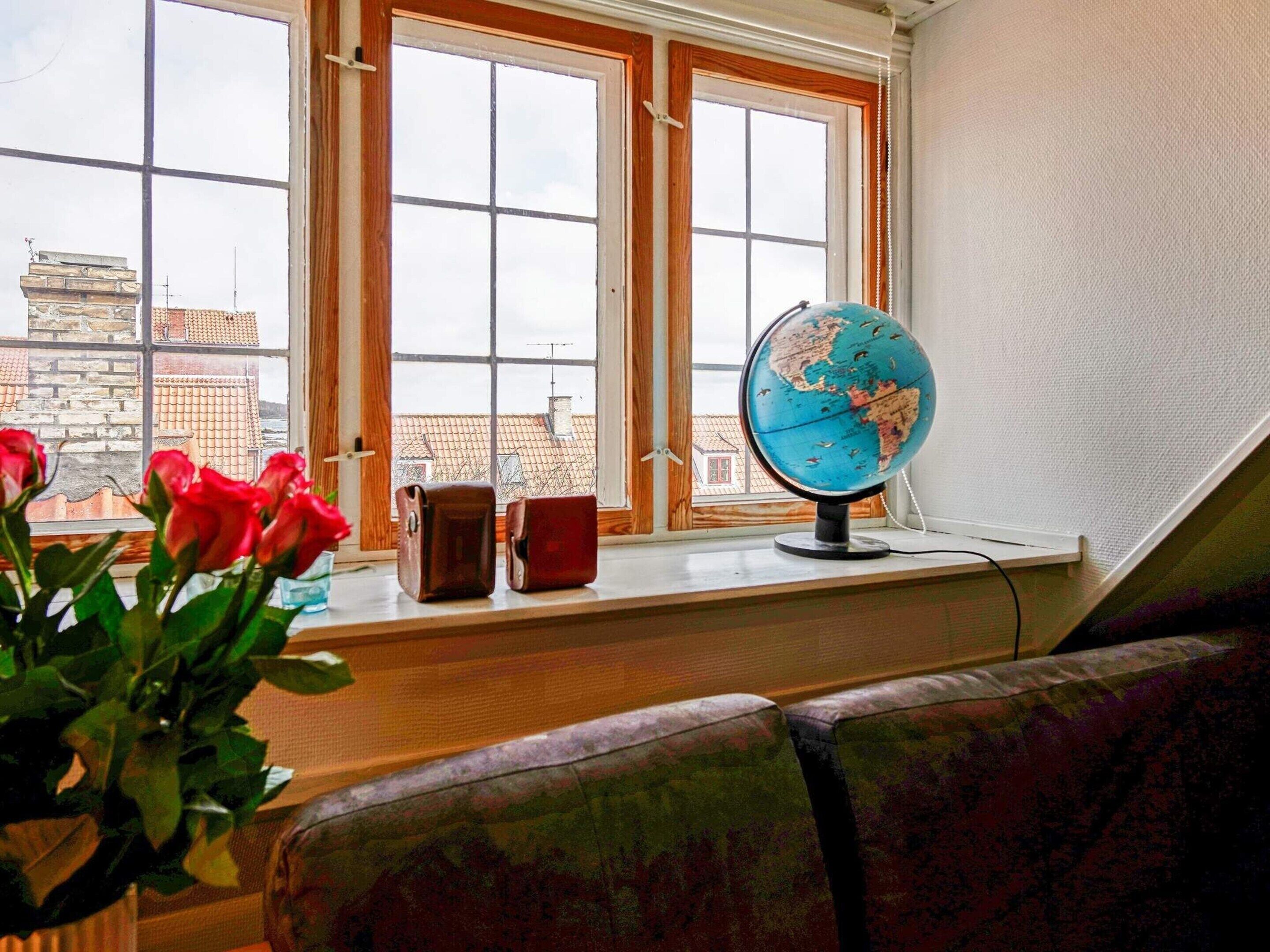 A room with a large window, a globe on a table, and a chair.