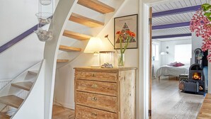 Une pièce chaleureuse avec un escalier en bois, une commode à tiroirs, une lampe et un tableau encadré accroché au mur.