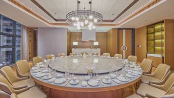 A conference room with a round table, beige chairs, and a modern chandelier.