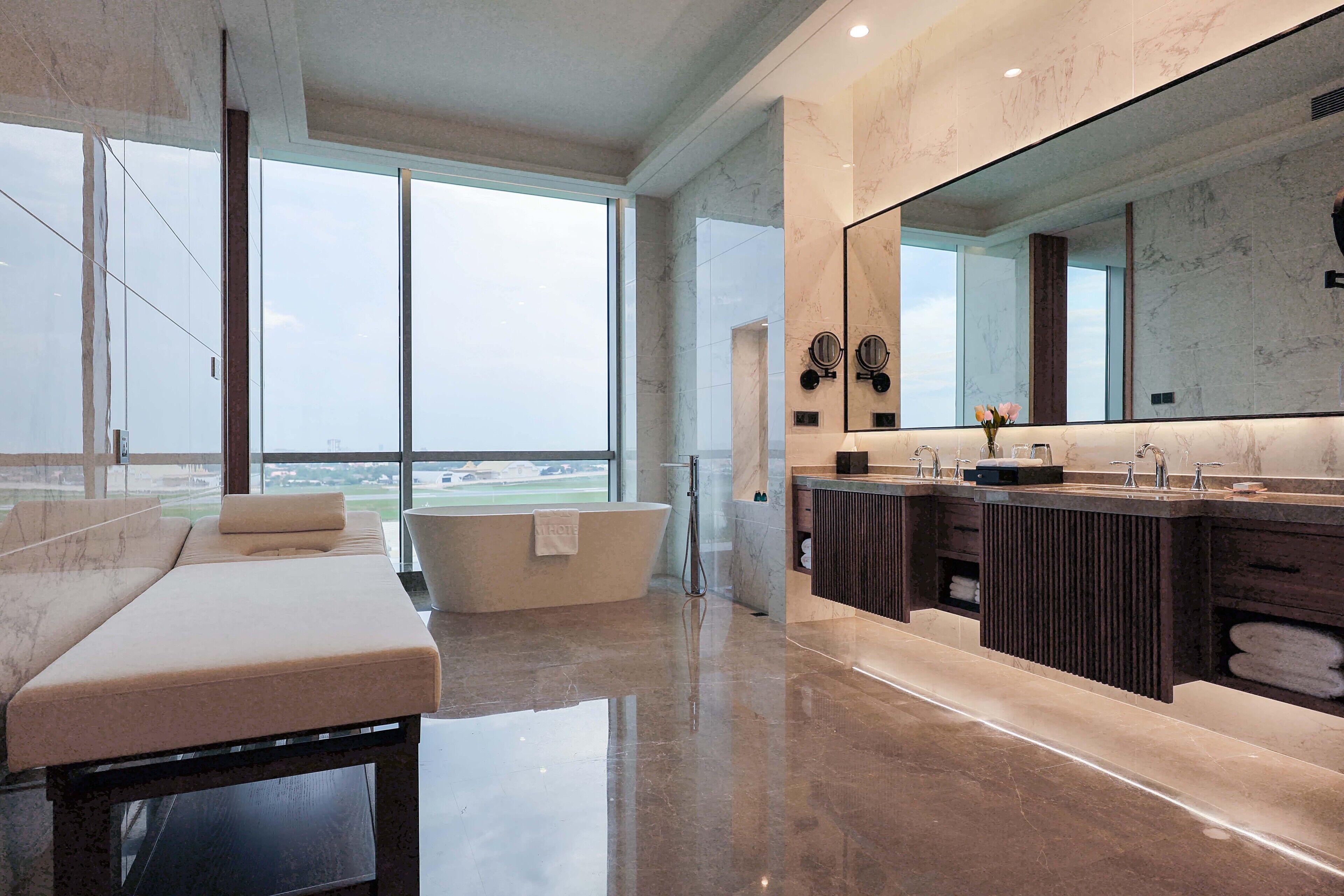 Un baño moderno con un espejo grande, una bañera y un tocador con un lavamanos espacioso.