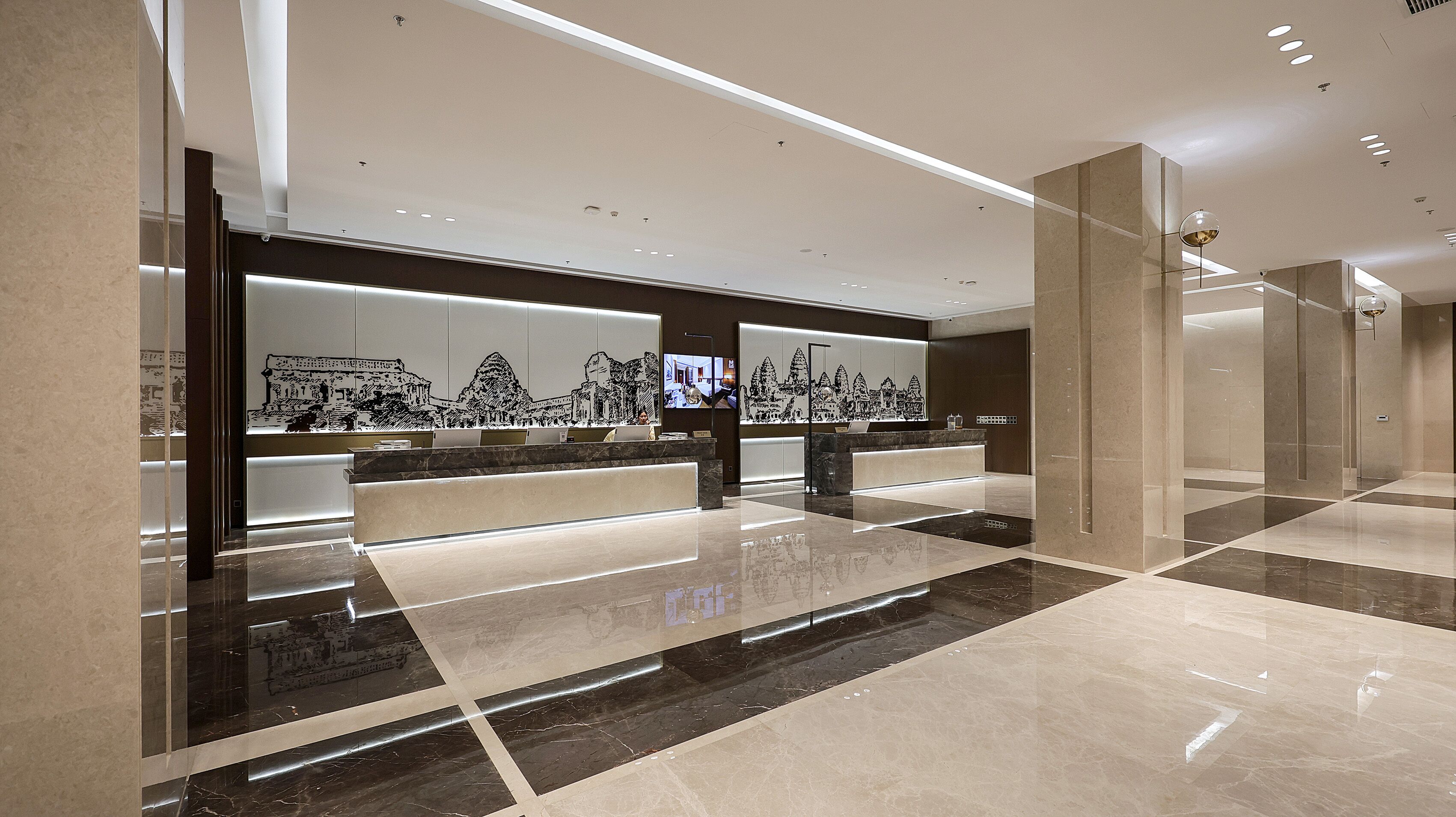 A modern reception area with marble flooring, a reception desk, and wall-mounted artwork depicting architectural structures.